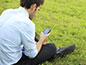 Male using his phone while sitting on grass
