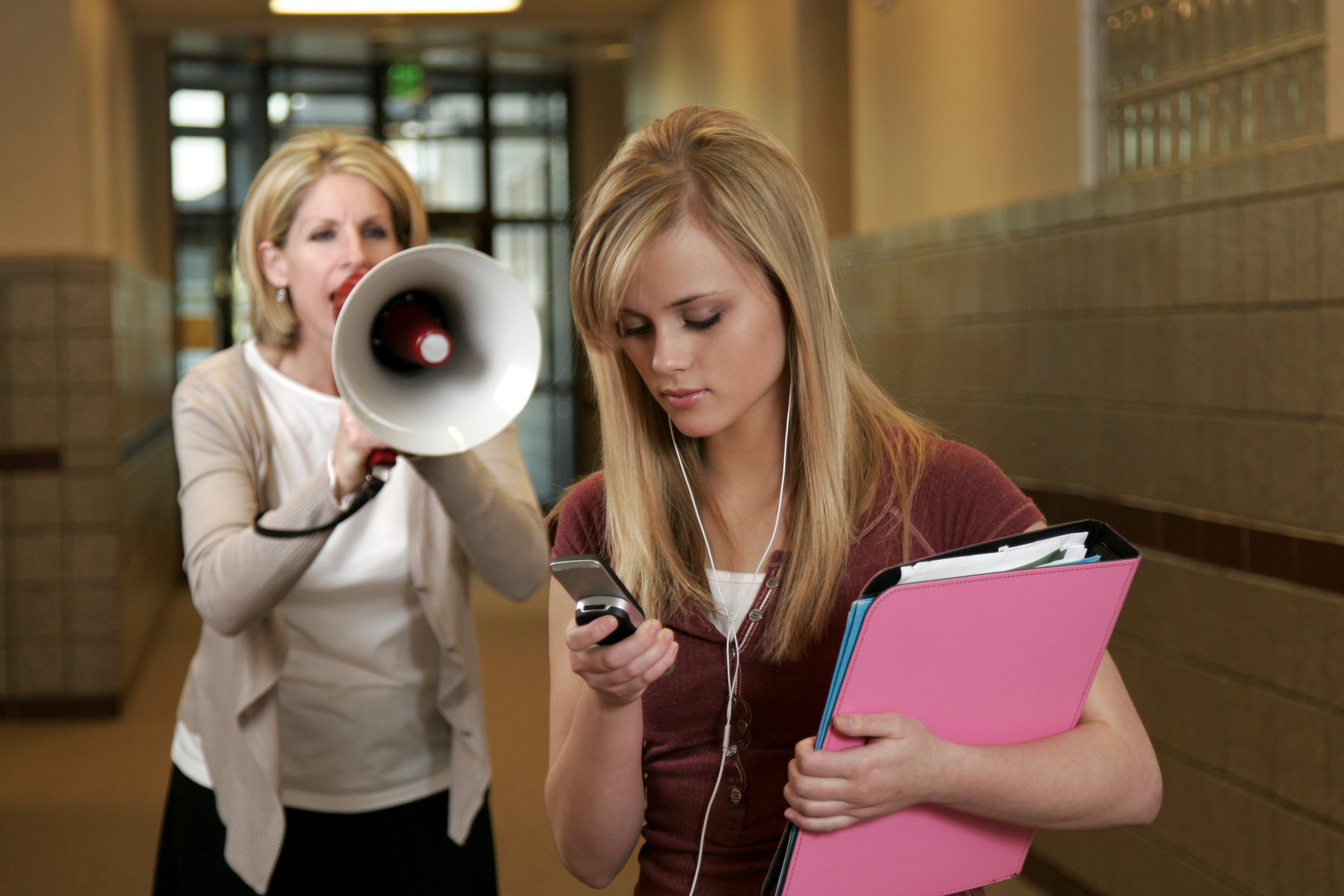principal is yelling at a distracted girl who is looking at her phone and is wearing earphones